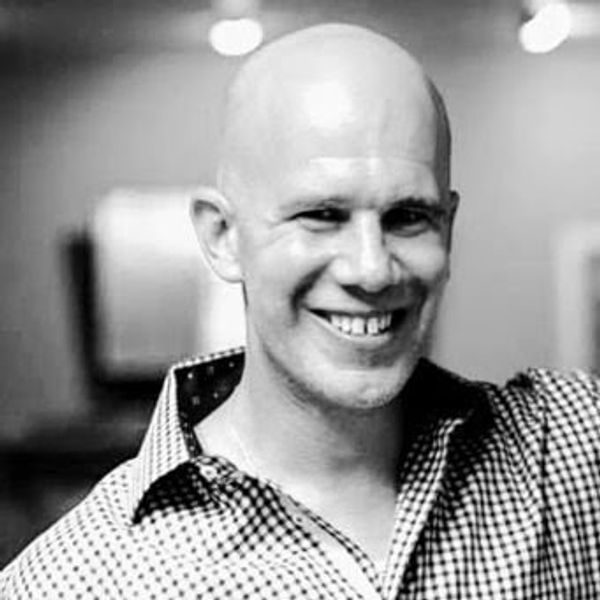 Smiling bald man in checkered shirt.