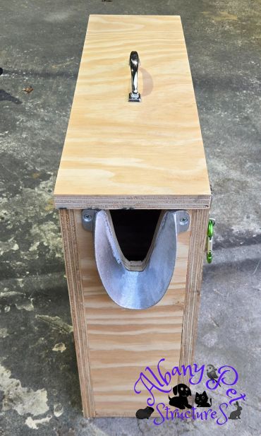Wooden pet carrier with a curved entrance and handle.