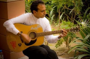 70s musician having a jam session outdoors on an acoustic guitar.
