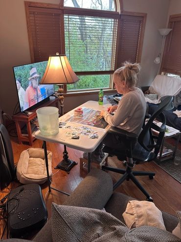 A woman working on a puzzle at a table in a cozy living room.