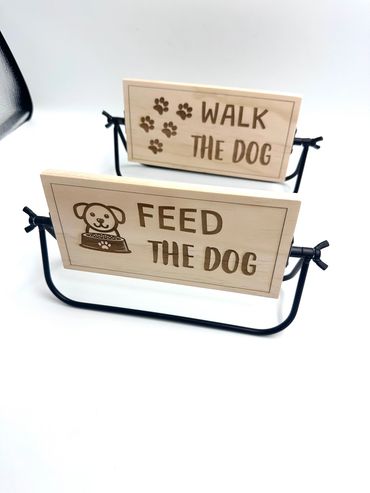 Wooden signs saying 'Feed the Dog' and 'Walk the Dog' on black metal stands.