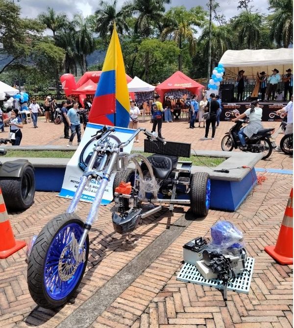Custom motorcycle displayed at an outdoor event with Colombian flag.