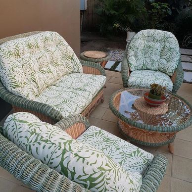 Wicker patio furniture set with green and white leaf-patterned cushions.