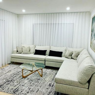Modern living room with a large light gray sectional sofa and a glass coffee table.
