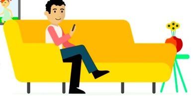 Man sitting on a yellow couch using a smartphone.