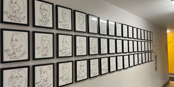 Wall of framed cartoon portraits in a hallway.