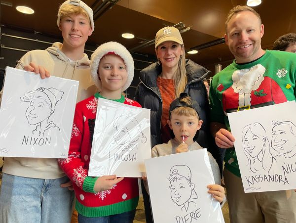 Family holding caricature drawings with holiday outfits.