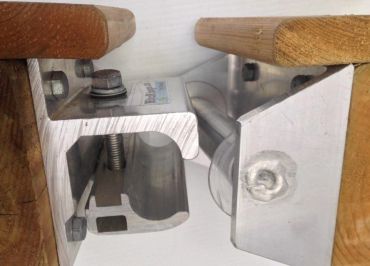 Close-up of a metal clamp mechanism secured to wooden surfaces.