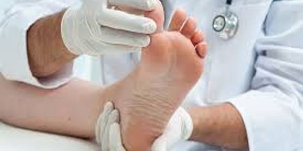 Doctor examining a patient's foot with gloves in a clinical setting.