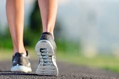 Close-up of a person walking or running on a road wearing black and white shoes.