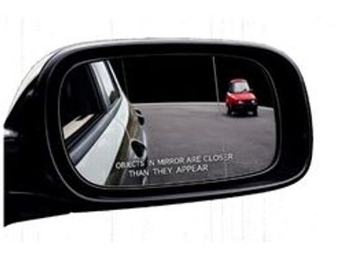 A car side mirror showing a red car behind with a warning text.