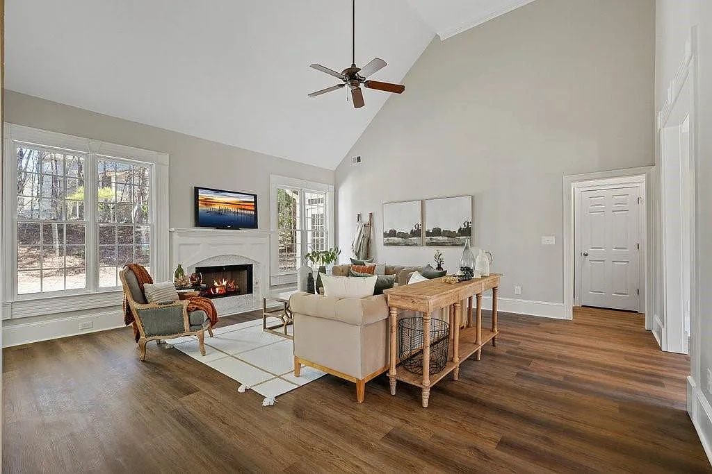 Bright living room with high ceilings, fireplace, and large windows.
