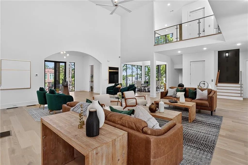 Modern spacious living room with leather sofas and green chairs.