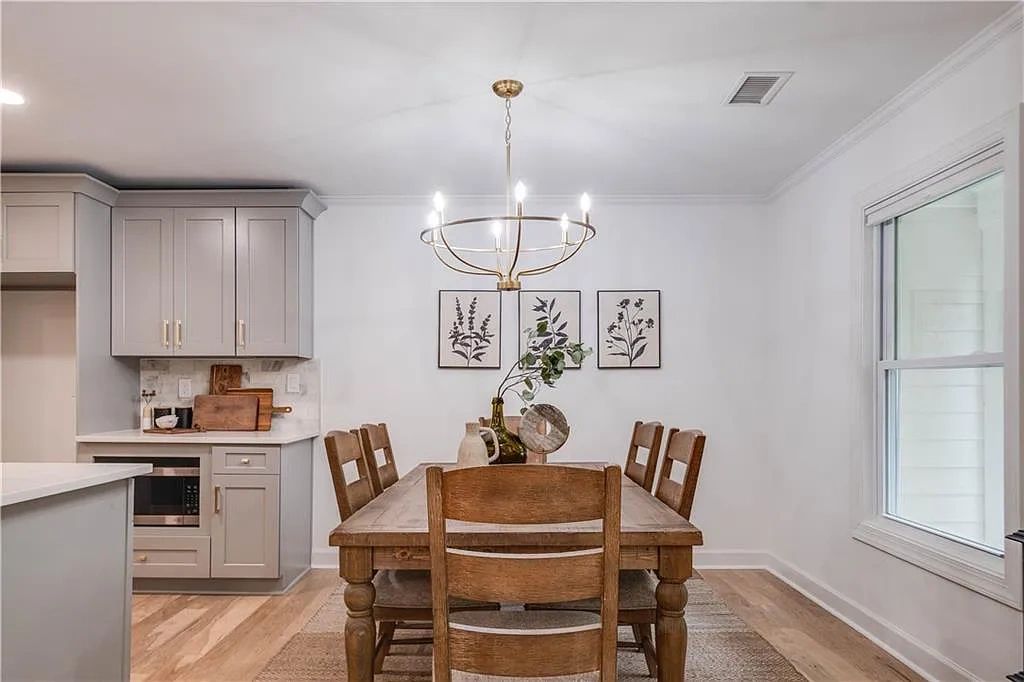 Cozy dining area with wooden table, chairs, and modern chandelier in a light, airy kitchen space.