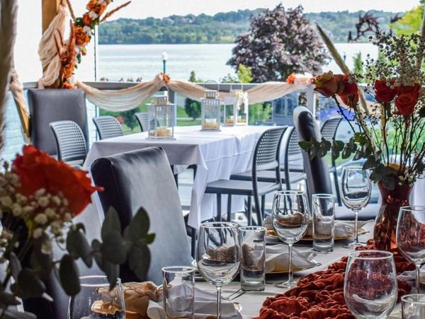 Elegant lakeside dining setup with floral decorations and glassware.