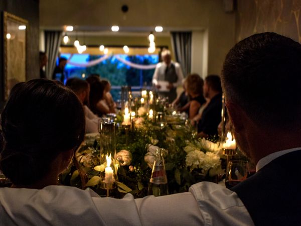 Intimate candlelit dinner with guests listening to a speaker.