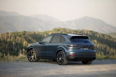 Blue SUV parked on a gravel road with mountains in the background.