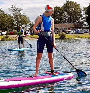 Person paddleboarding on calm water.