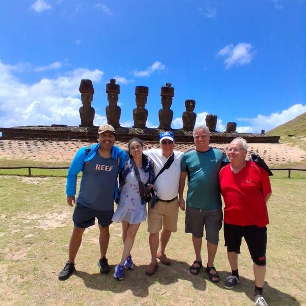 Five people posing in front of Easter Island moai statues under a clear blue sky.