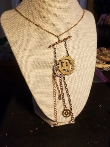 Steampunk-inspired necklace with gears and chains on a display bust.