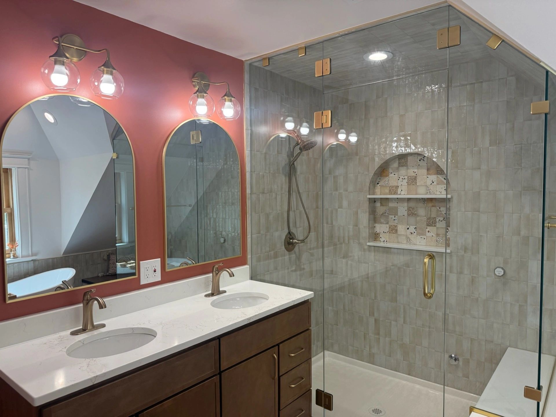Modern bathroom with dual sinks, arched mirrors, and glass shower.