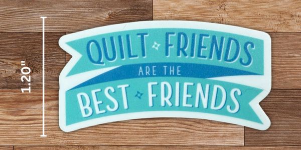 Sticker with the phrase 'Quilt Friends Are The Best Friends' on a wooden surface.