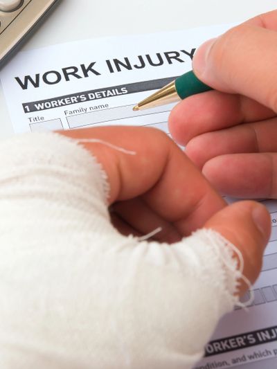 Person with bandaged hand filling out a work injury form.