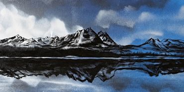 Black and white mountain landscape reflected in calm water under a cloudy sky.