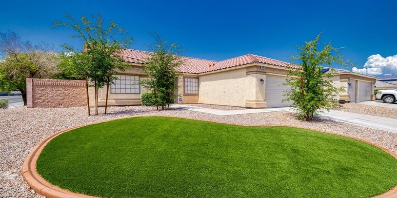 Light beige stucco ranch home 2-car garage front lawn desert landscape with grass area