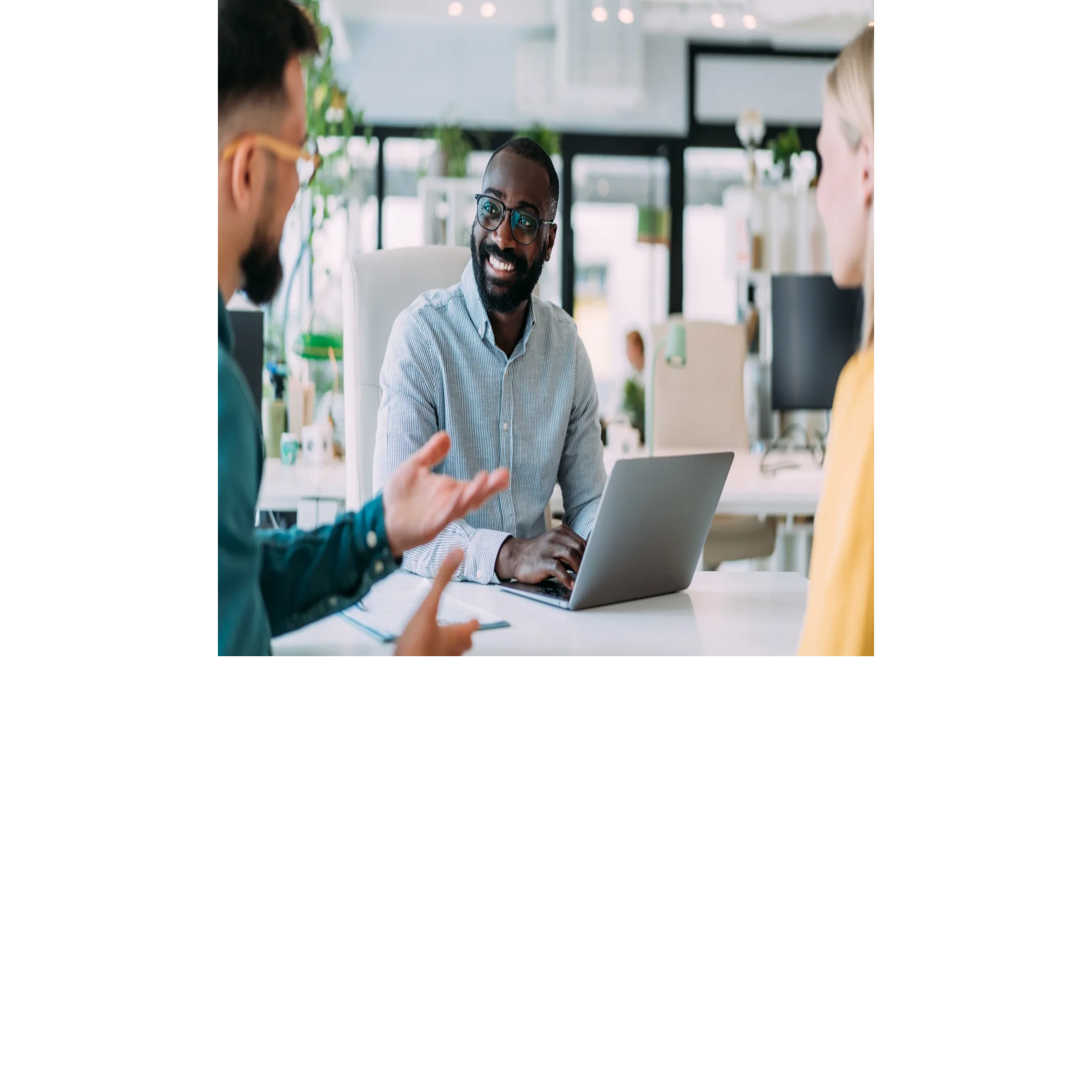 Three colleagues having a discussion with a laptop at work.