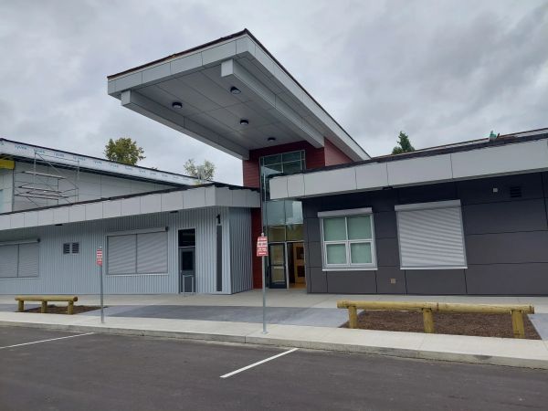 Modern building with covered entrance and parking spaces.
