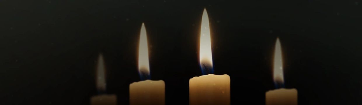 Three lit candles casting reflections on a dark, reflective surface.