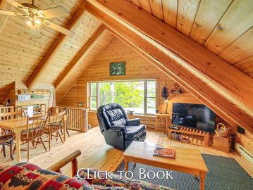 Cozy wooden cabin living room with recliner and TV under slanted ceiling.
