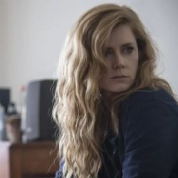 Woman with long wavy blonde hair looking to the side indoors.