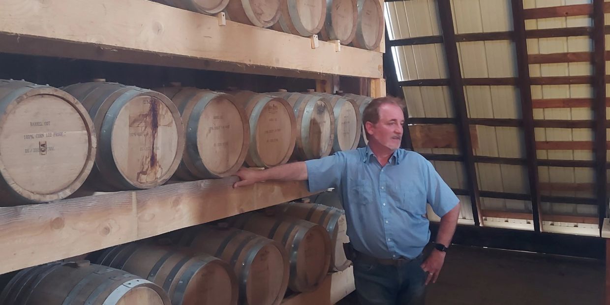 Man standing beside barrels in a warehouse.