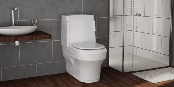 White Closomat toilet in bathroom next to shower and sink.
