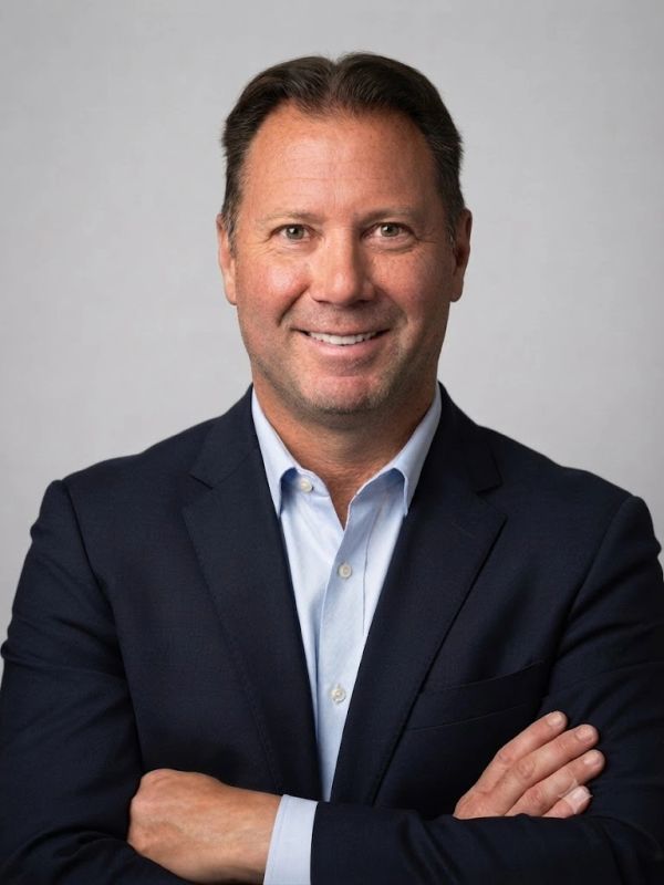 Smiling man in a blue suit with arms crossed.