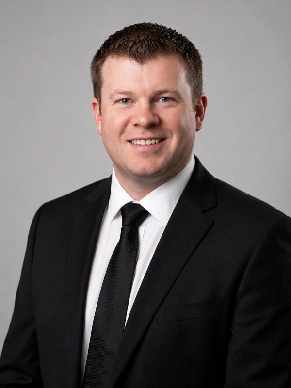 Professional man in a black suit and tie smiling.