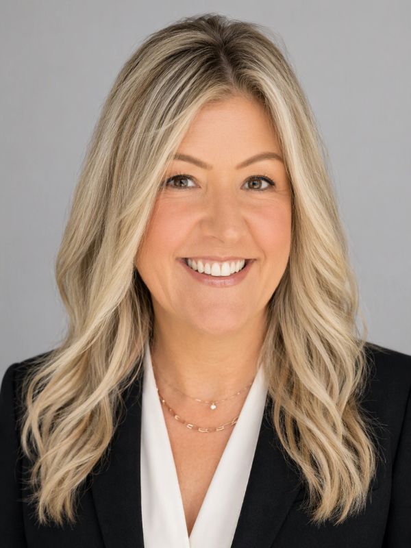 Smiling woman with blonde hair in business attire.