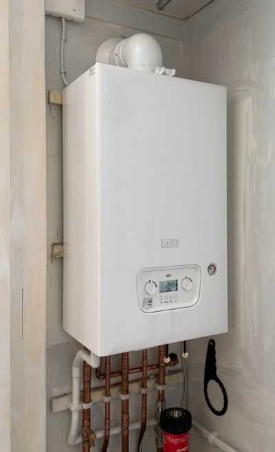 White wall-mounted boiler with copper pipes and digital control panel.