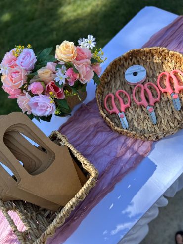 Floral arrangement and pink-handled scissors on a decorated table.