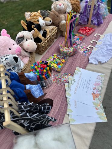 Craft table with stuffed animals, markers, beads, and craft supplies.