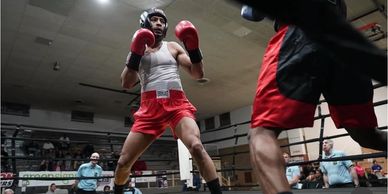 Two boxers in a ring, one preparing to punch, the other partially visible.