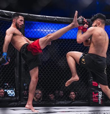 Two MMA fighters in the octagon during a high kick exchange.