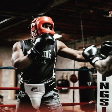Boxer in red headgear throwing a punch inside a boxing ring.