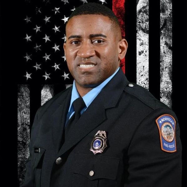 Portrait of a firefighter in uniform with an American flag backdrop.