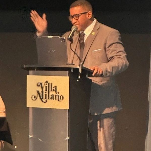 Man in suit speaking passionately at a podium with a microphone.