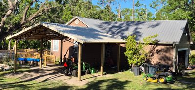 Newly built covered structure on a concrete slab next to a ramp/ fence leading to a pool.