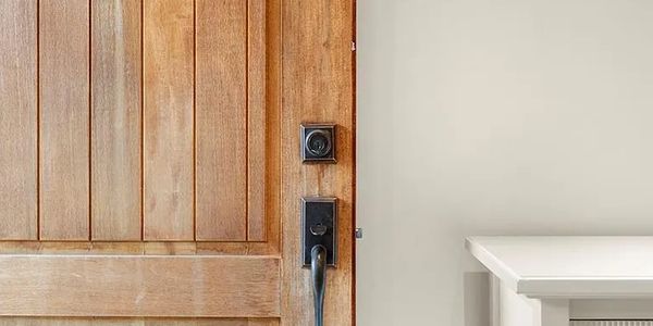 Close-up of a wooden door with modern black handle and lock.