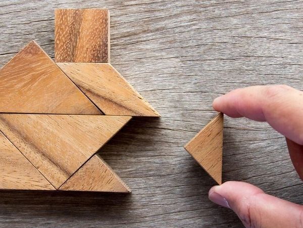 Hand placing final piece in wood tangram